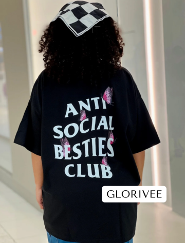 Woman standing in a mall wearing the AntiSocial Besties Club Butterfly Tee by Dass My Best Friend, showing the back design of the tee. The butterfly details add a playful twist to the iconic design, perfect for introverted best friends with an edgy style.