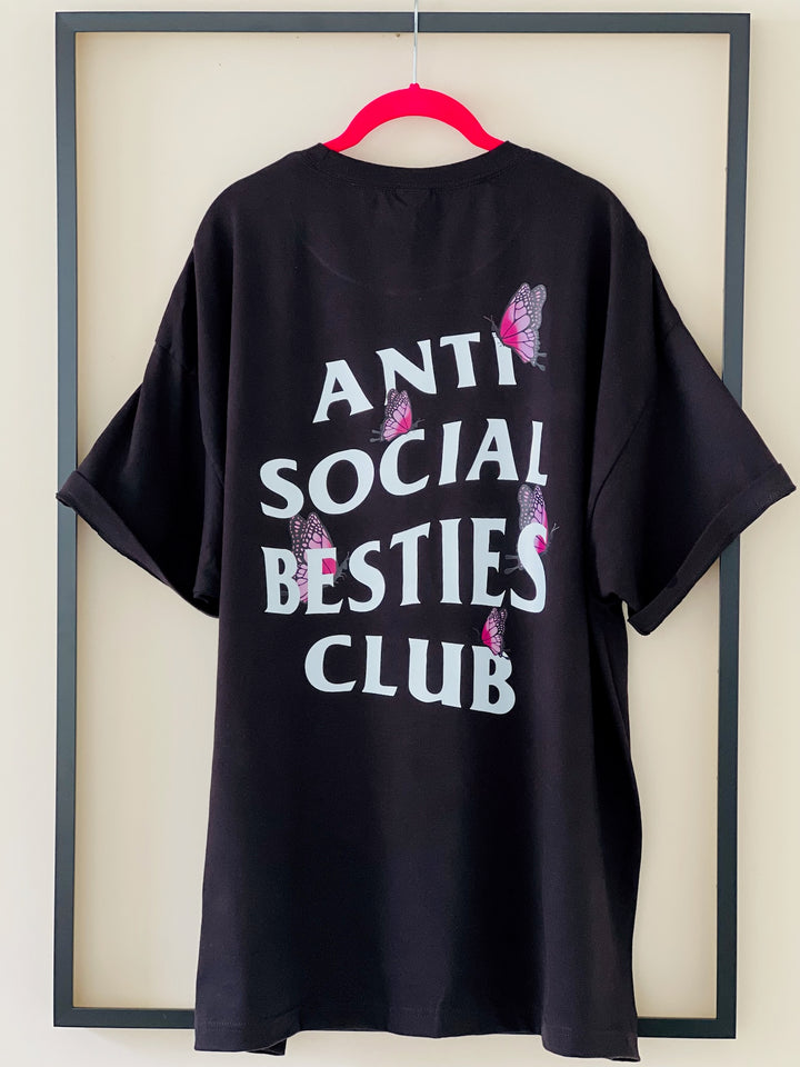 Back view of the AntiSocial Besties Club Butterfly Tee by Dass My Best Friend, hanging inside a picture frame. The butterfly details and bold design are showcased, highlighting the playful and edgy spirit of this tee for best friends.