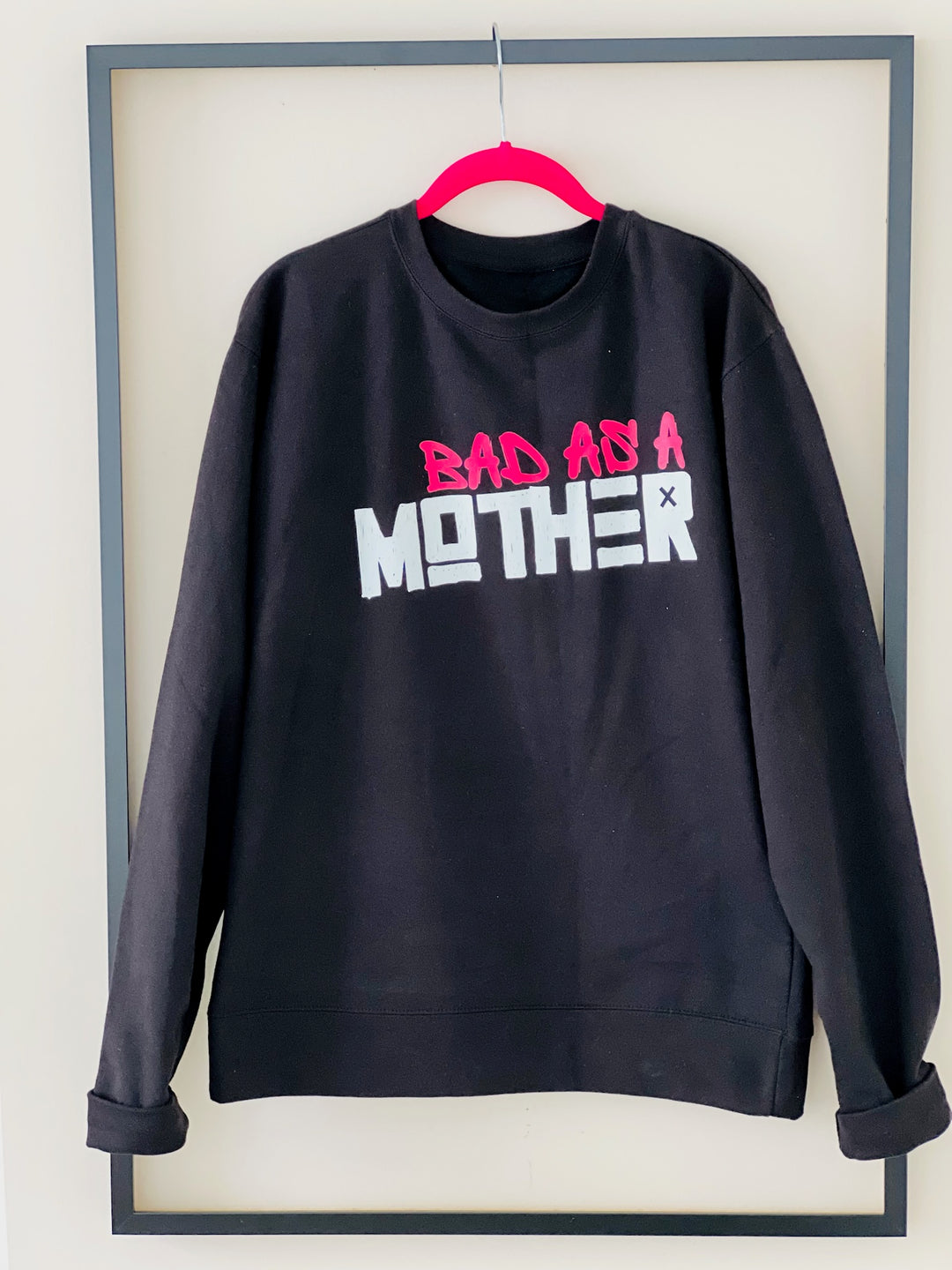 Dass My Best Friend Bad As A Mother graphic sweatshirt in black and gray, hanging inside a picture frame. The bold design and comfortable midweight cotton blend are showcased, perfect for moms who embrace style and confidence in their everyday lives.