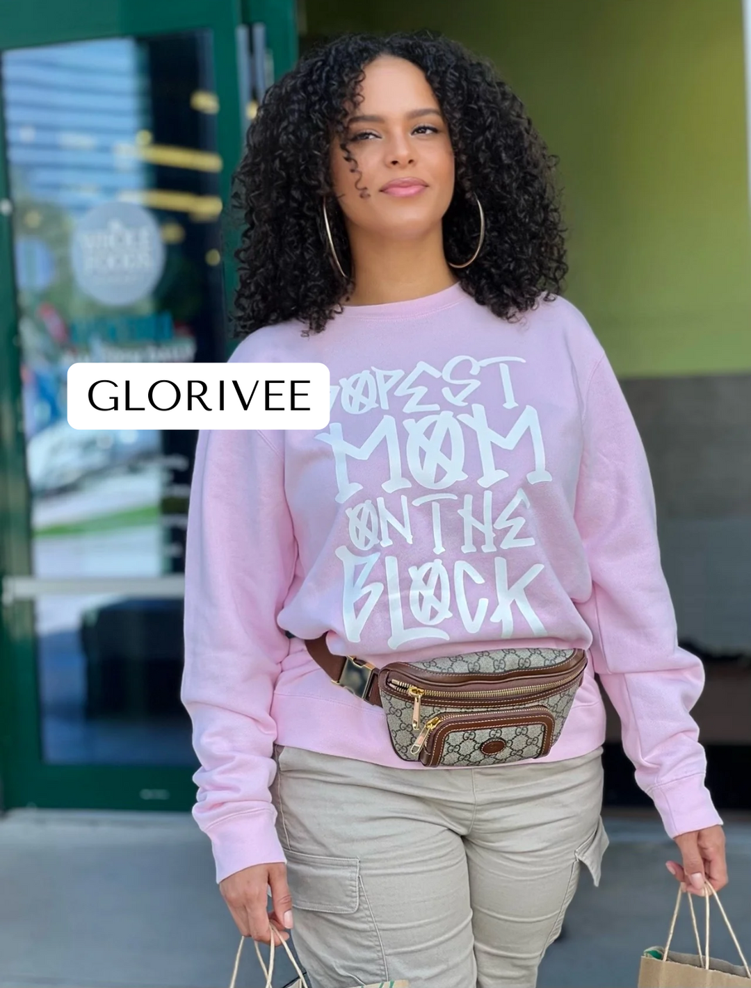 Close-up of Glorivee wearing the pink "Dopest Mom on the Block" sweatshirt by Dass My Best Friend while shopping at Whole Foods. The sweatshirt radiates confidence and style, making it the perfect choice for busy and fashionable moms.