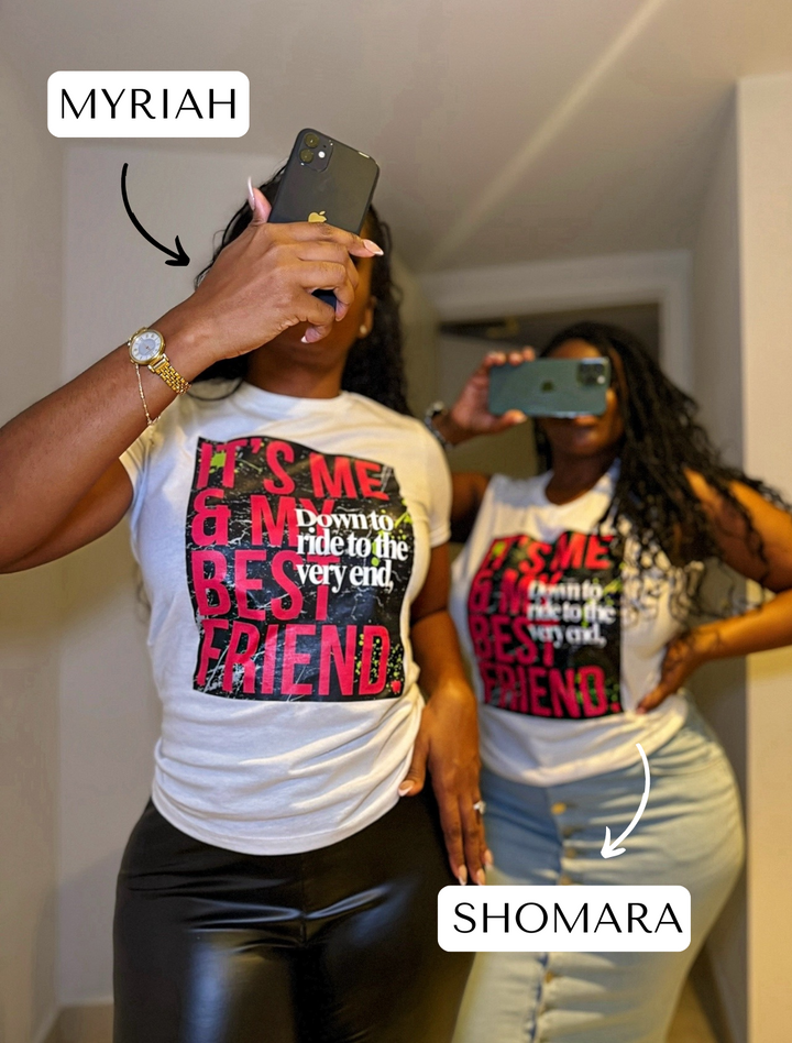 Shomara and Myriah are wearing the "Down to Ride" T-shirt by Dass My Best Friend, with one woman playfully peeking through her fingers. The feminine-fitted tee showcases the bold "Down to Ride" design, celebrating best friends who are always up for adventure.