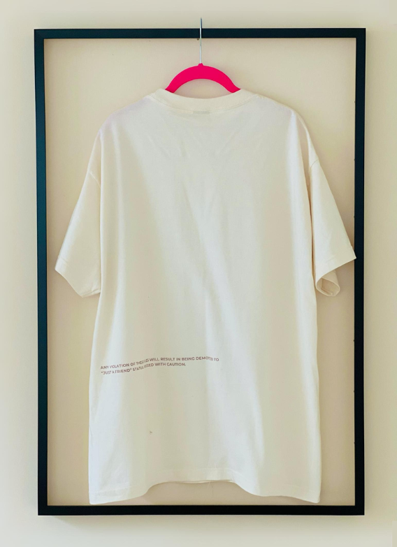 Full back view of the tan "That's My Best Friend" Tee by Dass My Best Friend, hanging inside a picture frame. The bold "That's My Best Friend" design is printed on the back, showcasing the relaxed fit and celebrating the unbreakable bond with your best friend.